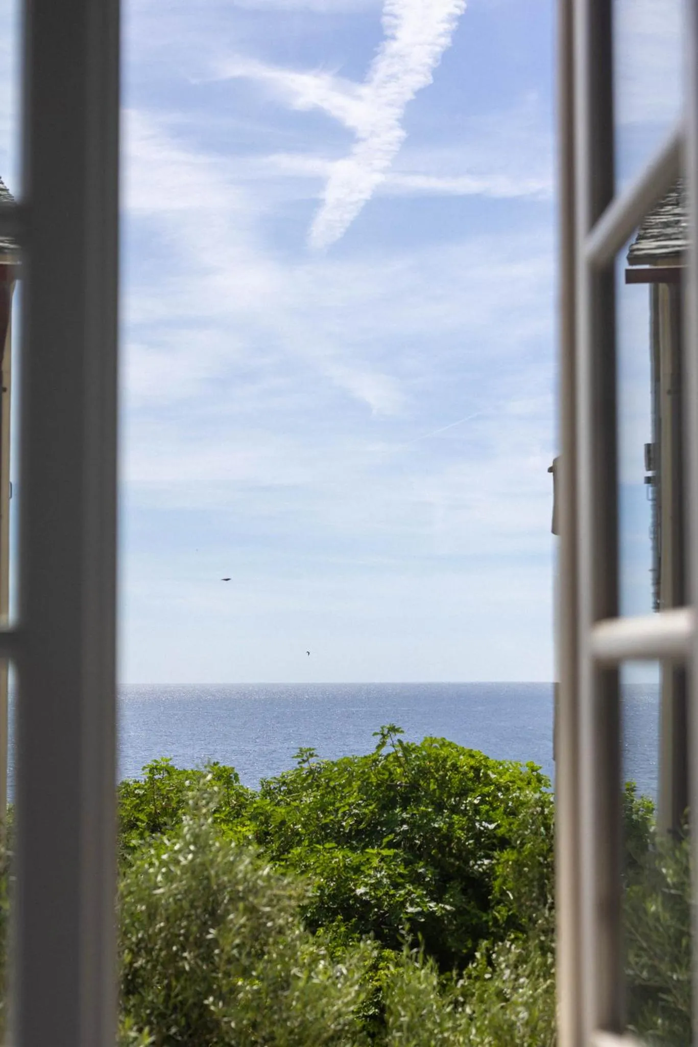 Vue sur la mer depuis une fenêtre ouverte.