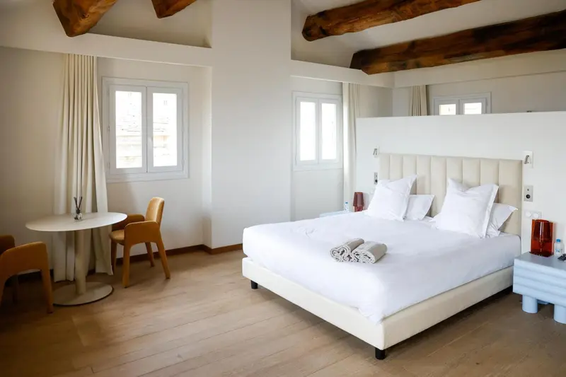 Une chambre lumineuse avec un lit double et un coin repas.
