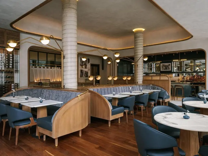 Une salle de restaurant lumineuse avec des tables et des banquettes bleues.