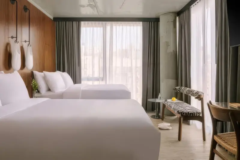 Une chambre lumineuse avec deux lits simples et un coin salon.