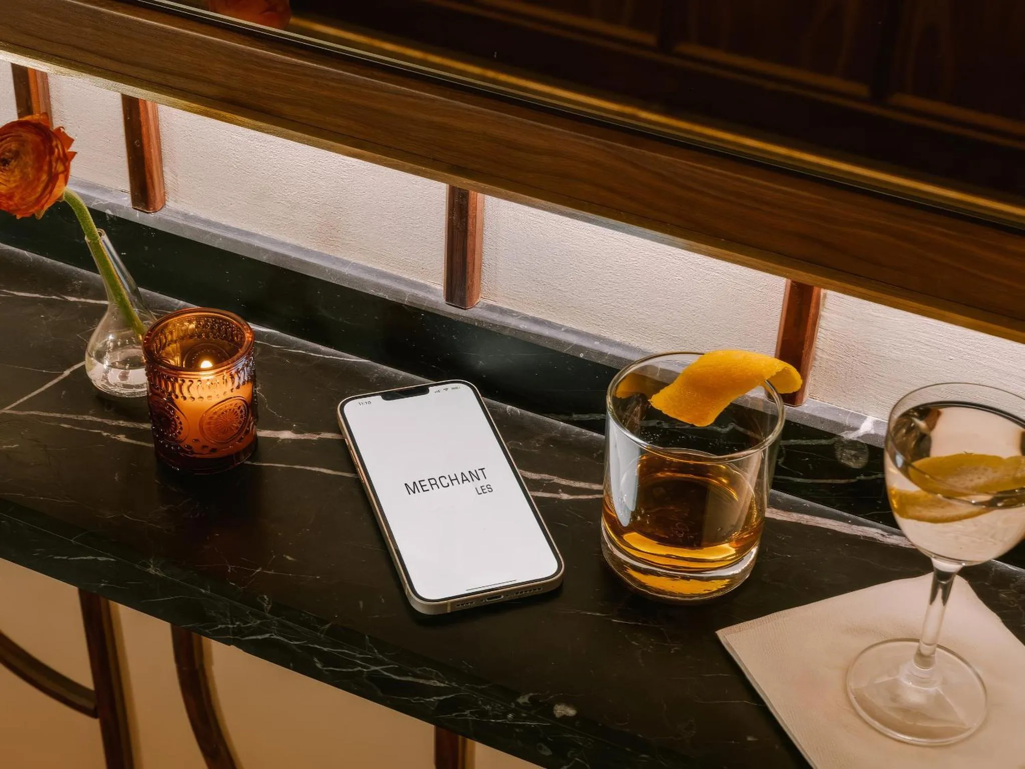 Une table sombre présente des verres à cocktail et un téléphone portable.