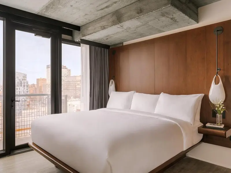 Une chambre lumineuse avec un grand lit et une vue sur la ville.