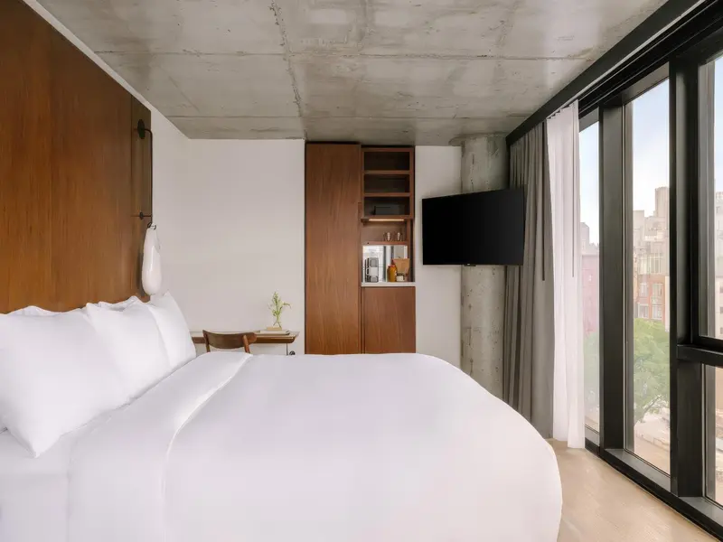 Une chambre lumineuse avec un grand lit et une vue sur la ville.
