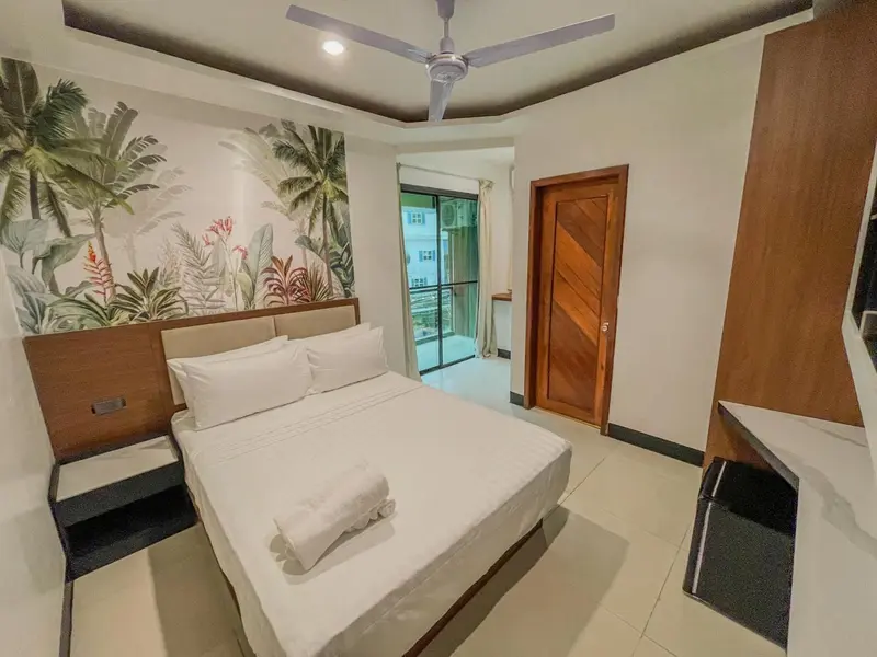 Une chambre lumineuse avec un grand lit et un décor tropical.
