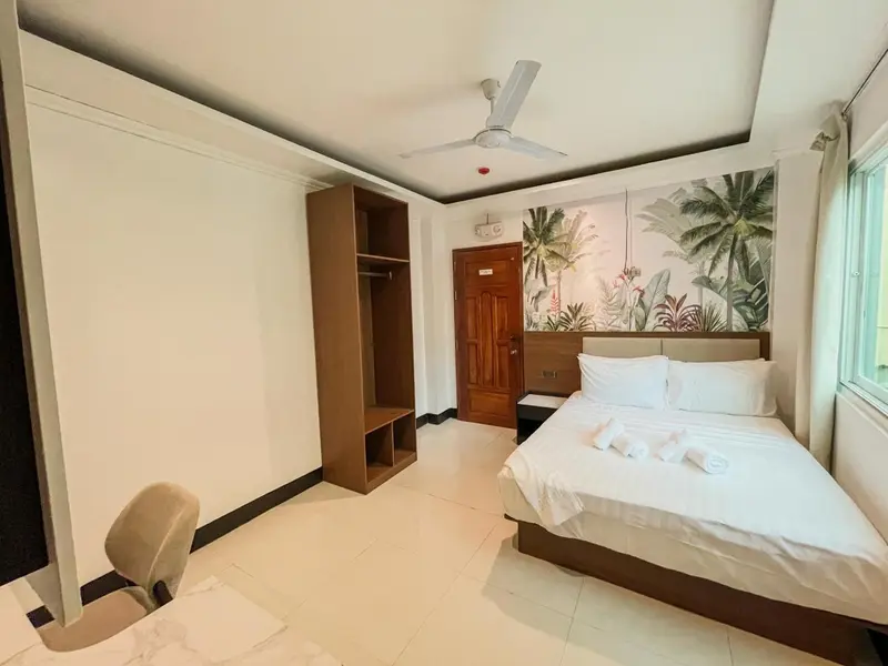 Une chambre lumineuse avec un grand lit et un décor tropical.