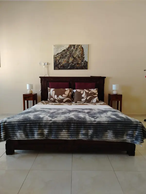 Une chambre avec un grand lit recouvert d'une couverture texturée et décorée de coussins.
