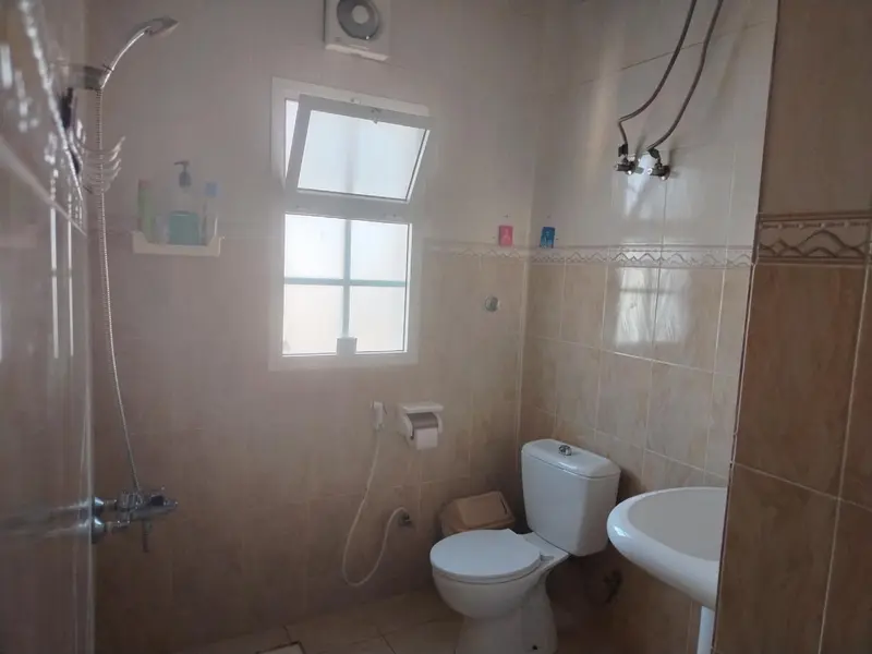 Une salle de bain claire avec douche, lavabo et toilettes.