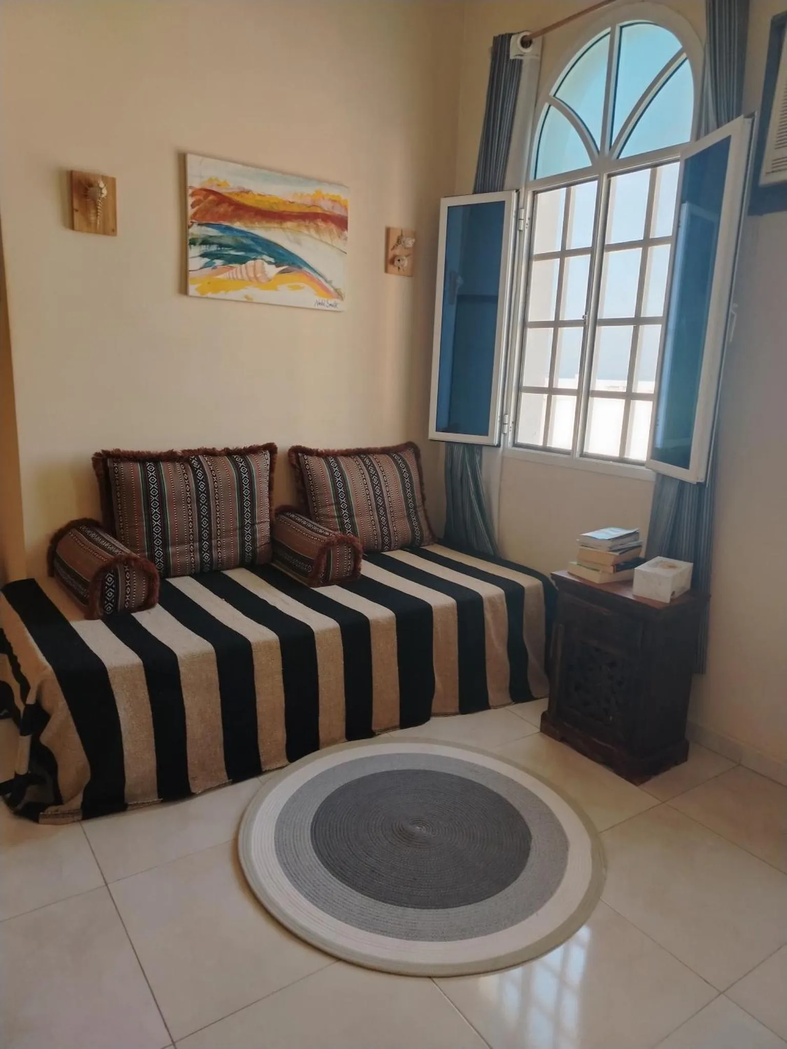 Espace de détente avec coussins rayés et vue sur la mer.