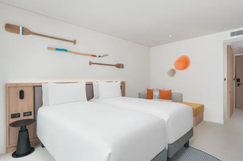 Une chambre lumineuse avec un grand lit et une décoration murale colorée.