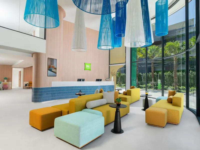Un hall d'accueil lumineux avec un comptoir et des assises colorées.
