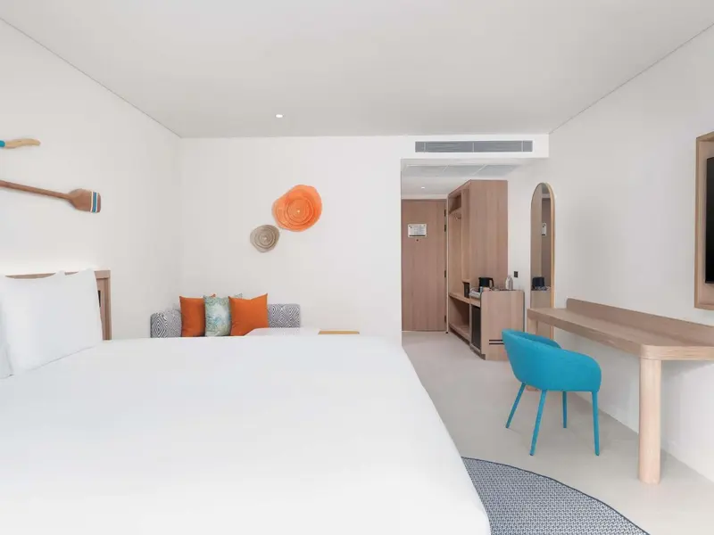 Chambre lumineuse avec un grand lit et un bureau bleu turquoise.
