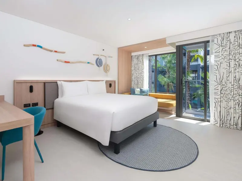 Une chambre lumineuse avec un grand lit et un accès à une terrasse.