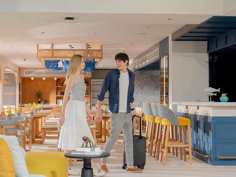 Un couple se promène dans un hall d'hôtel moderne avec un bar.