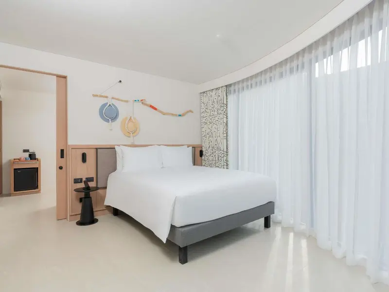 Une chambre lumineuse avec un grand lit blanc et une décoration murale.