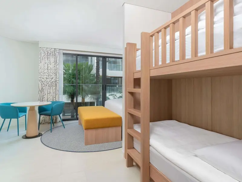 Une chambre lumineuse avec un lit superposé et un coin repas.