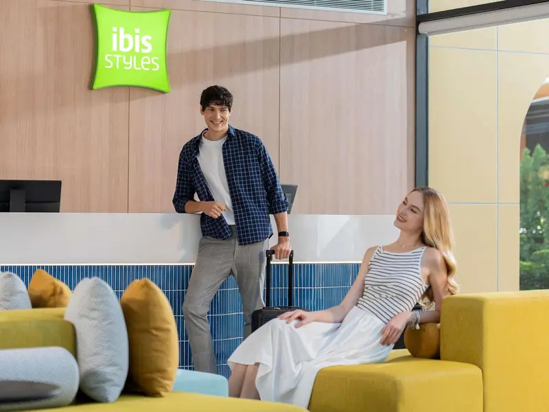 Un couple souriant se trouve près du comptoir d'accueil d'un hôtel.