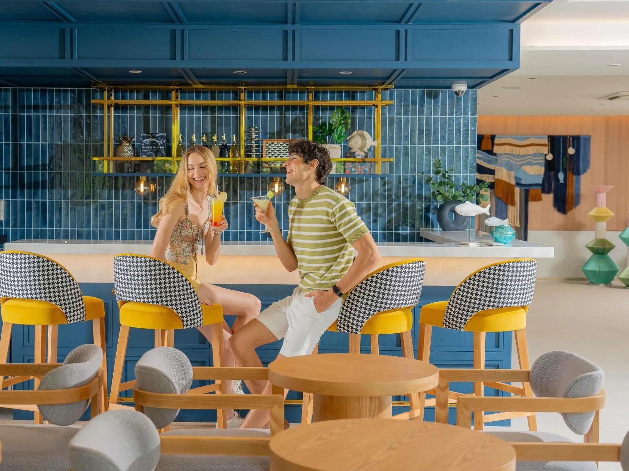 Un couple souriant déguste des boissons au comptoir d'un bar décoré de manière moderne.
