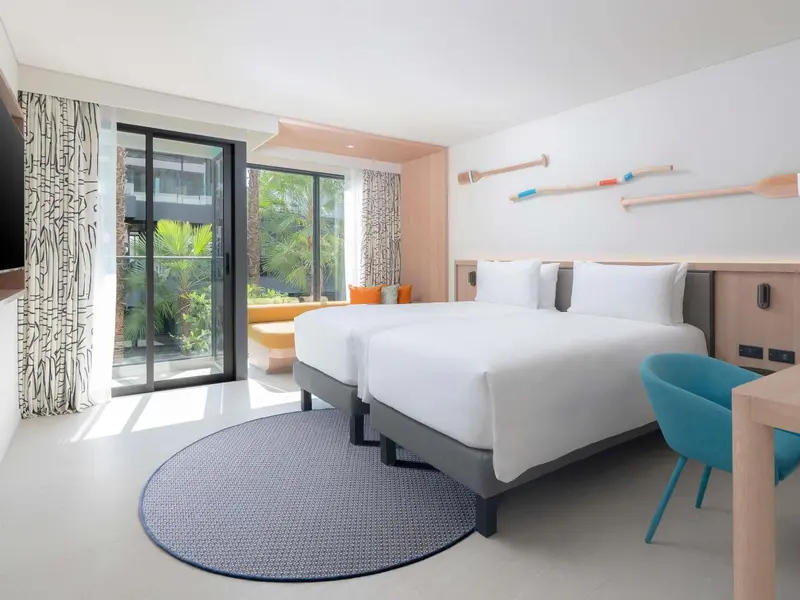 Une chambre lumineuse avec deux lits simples et un accès à une terrasse.