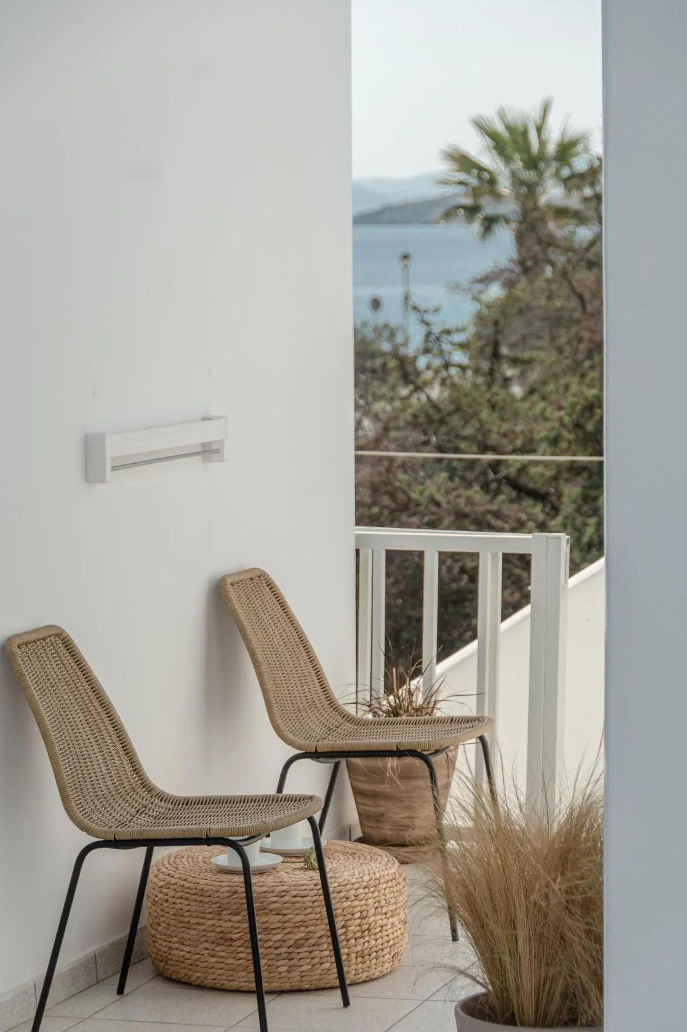 Deux fauteuils en osier sur une terrasse avec vue sur la mer.