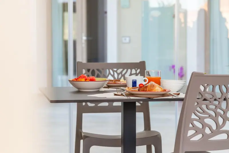 Une table est dressée avec un petit-déjeuner composé de fruits, de viennoiseries et d'une boisson.