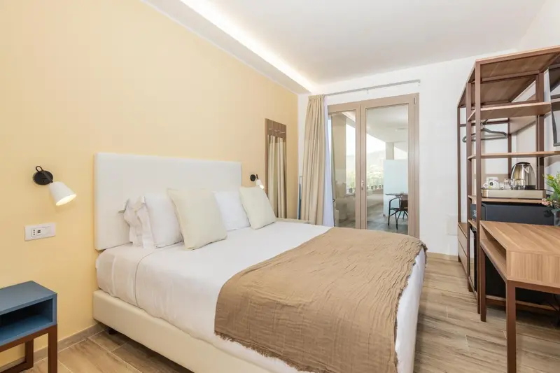 Une chambre lumineuse avec un grand lit et un accès à une terrasse.