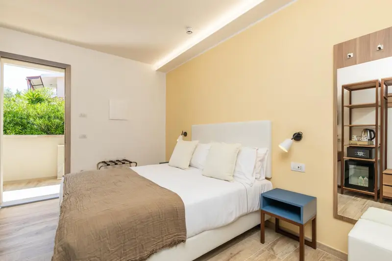 Chambre lumineuse avec un grand lit et une vue sur l'extérieur.