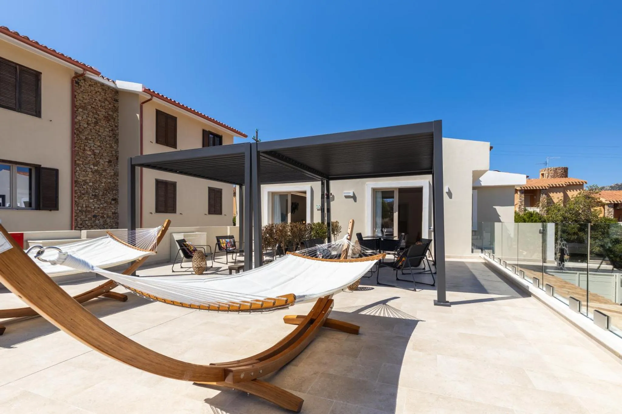 Terrasse ombragée avec des hamacs et des fauteuils de jardin.