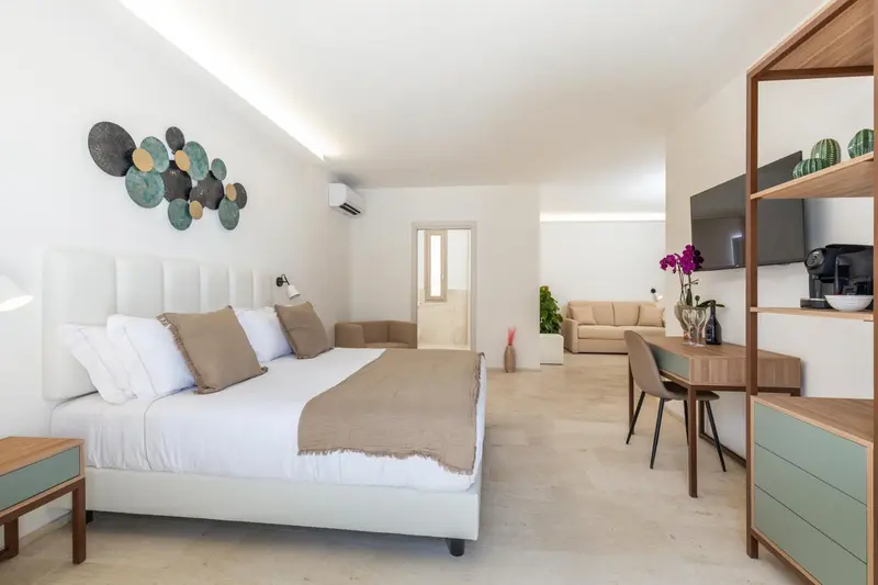 Une chambre lumineuse avec un grand lit et un espace salon.