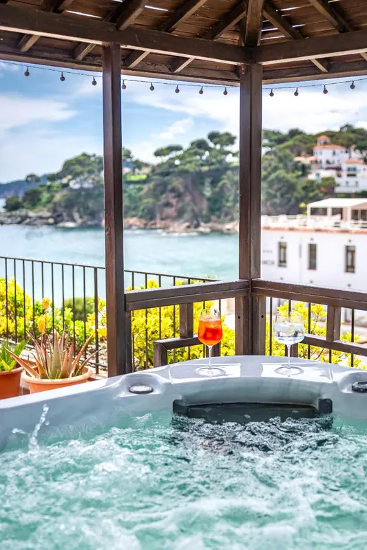 Un jacuzzi sur une terrasse avec vue sur la mer et la côte.