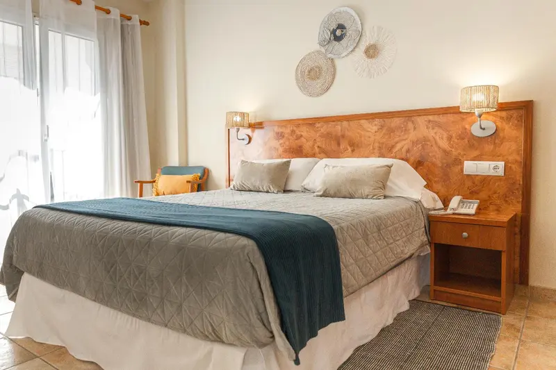 Une chambre lumineuse avec un grand lit recouvert d'une couverture.