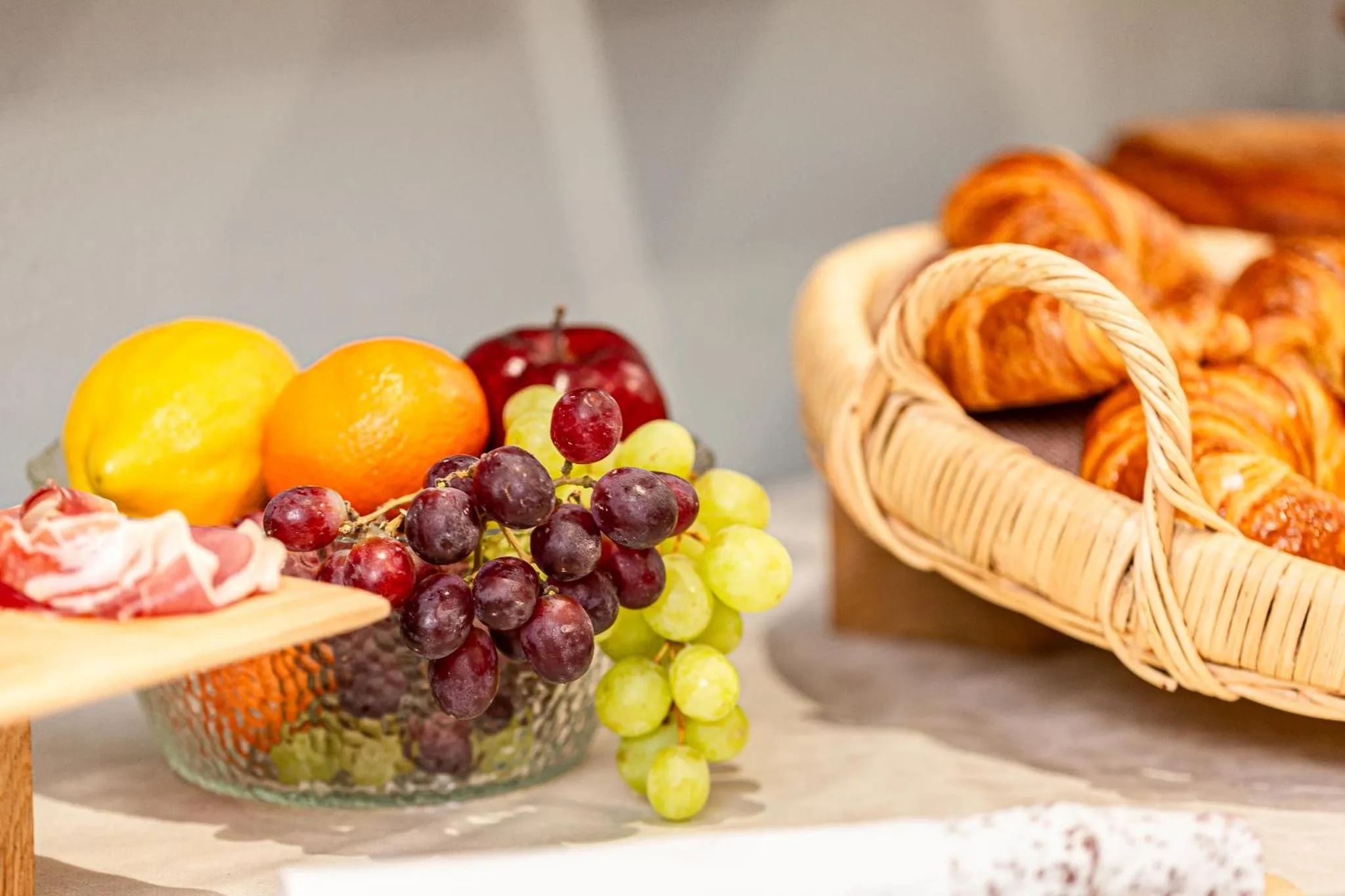 Une sélection de viennoiseries, de fruits frais et de charcuterie est présentée sur un buffet.