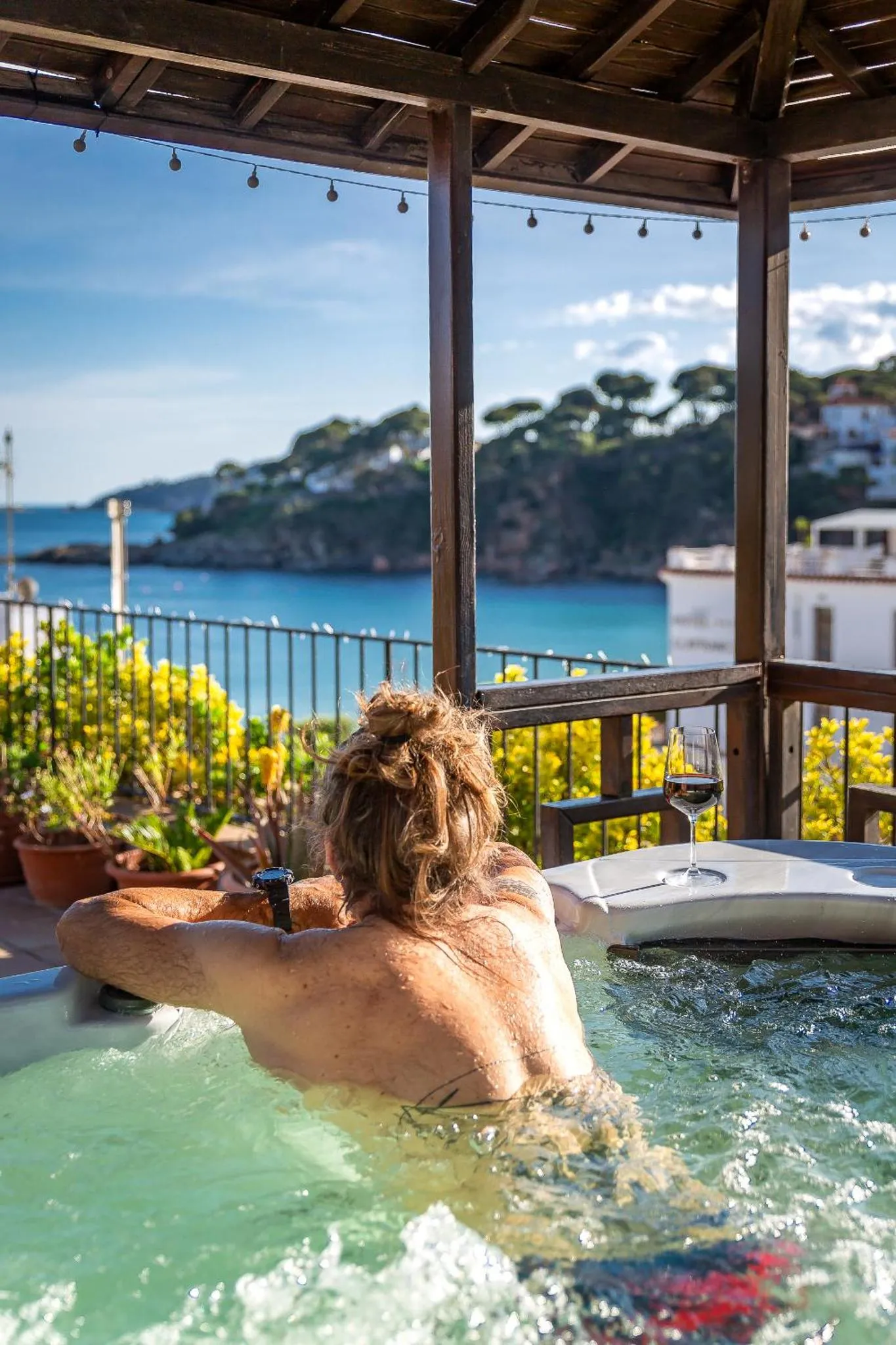 Une personne se détend dans un jacuzzi avec vue sur la mer et la côte.