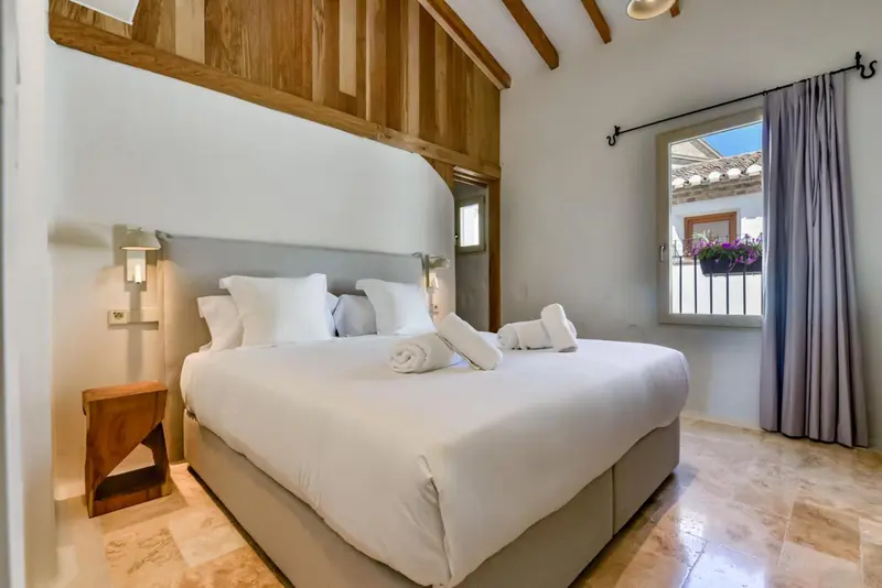Une chambre lumineuse avec un grand lit recouvert de draps blancs et de coussins.