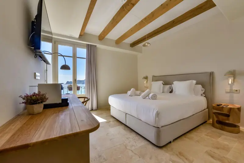 Une chambre lumineuse avec un lit double et un bureau en bois.