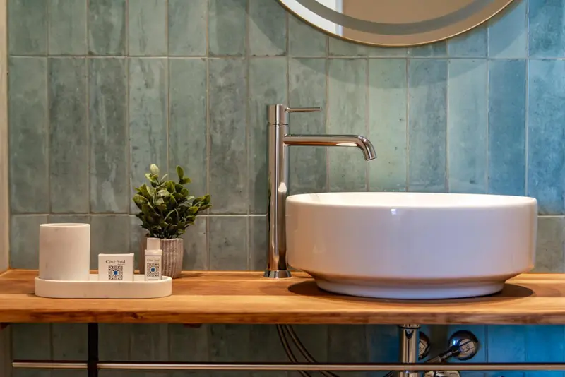 Un lavabo blanc sur un meuble en bois, avec des accessoires de toilette.