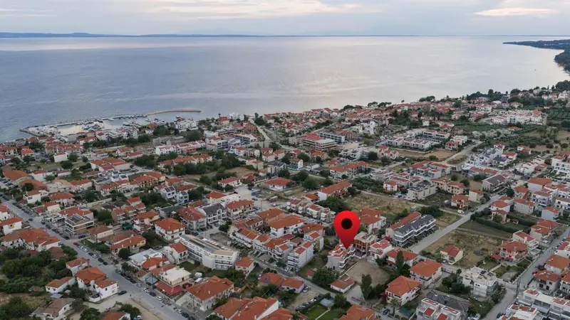 Vue aérienne d'une station balnéaire avec des bâtiments aux toits rouges et la mer en arrière-plan.