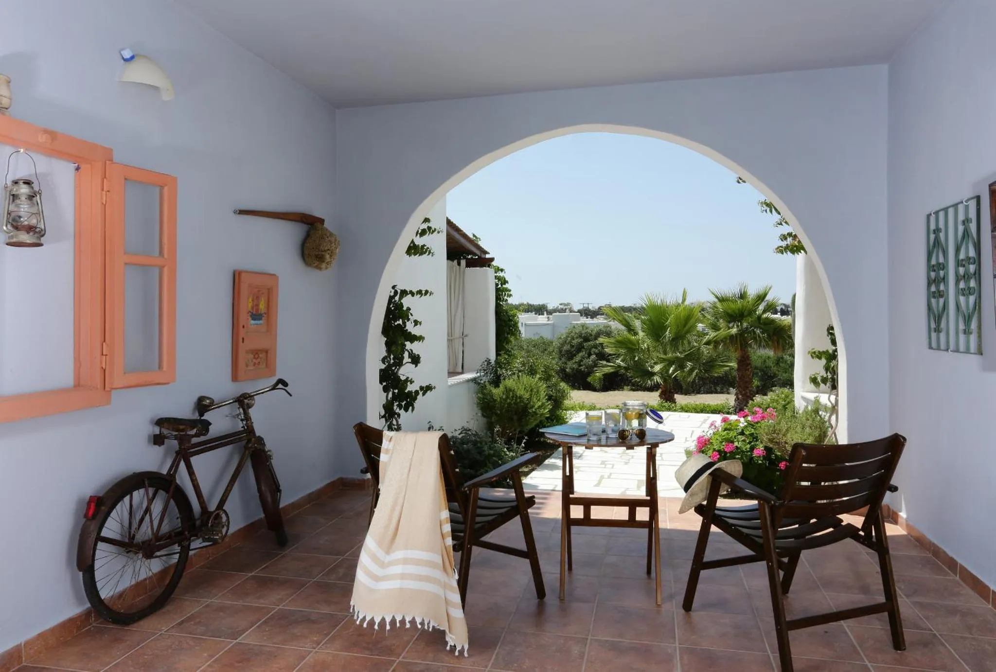 Une terrasse ombragée s'ouvre sur une cour intérieure verdoyante.