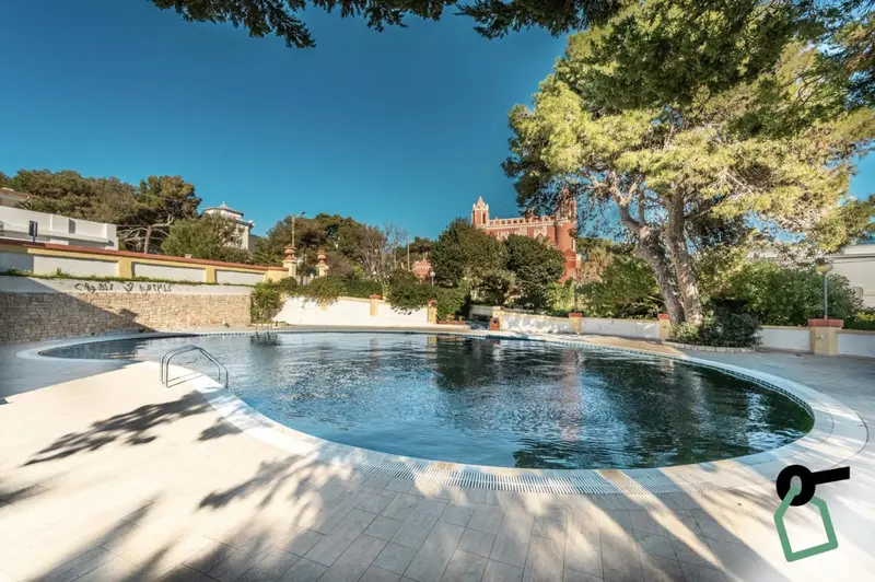 Une piscine rectangulaire entourée d'une terrasse carrelée et bordée de végétation.