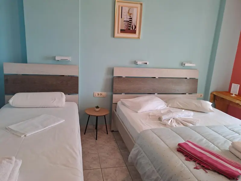 Deux lits simples avec linge blanc dans une chambre lumineuse.