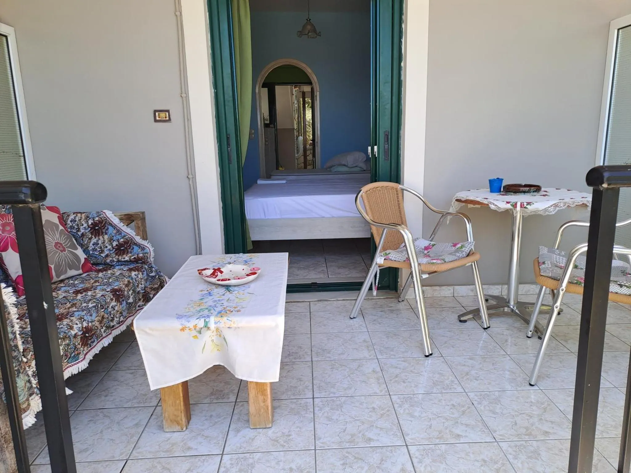 Une terrasse avec un canapé et une table basse donne sur une chambre.