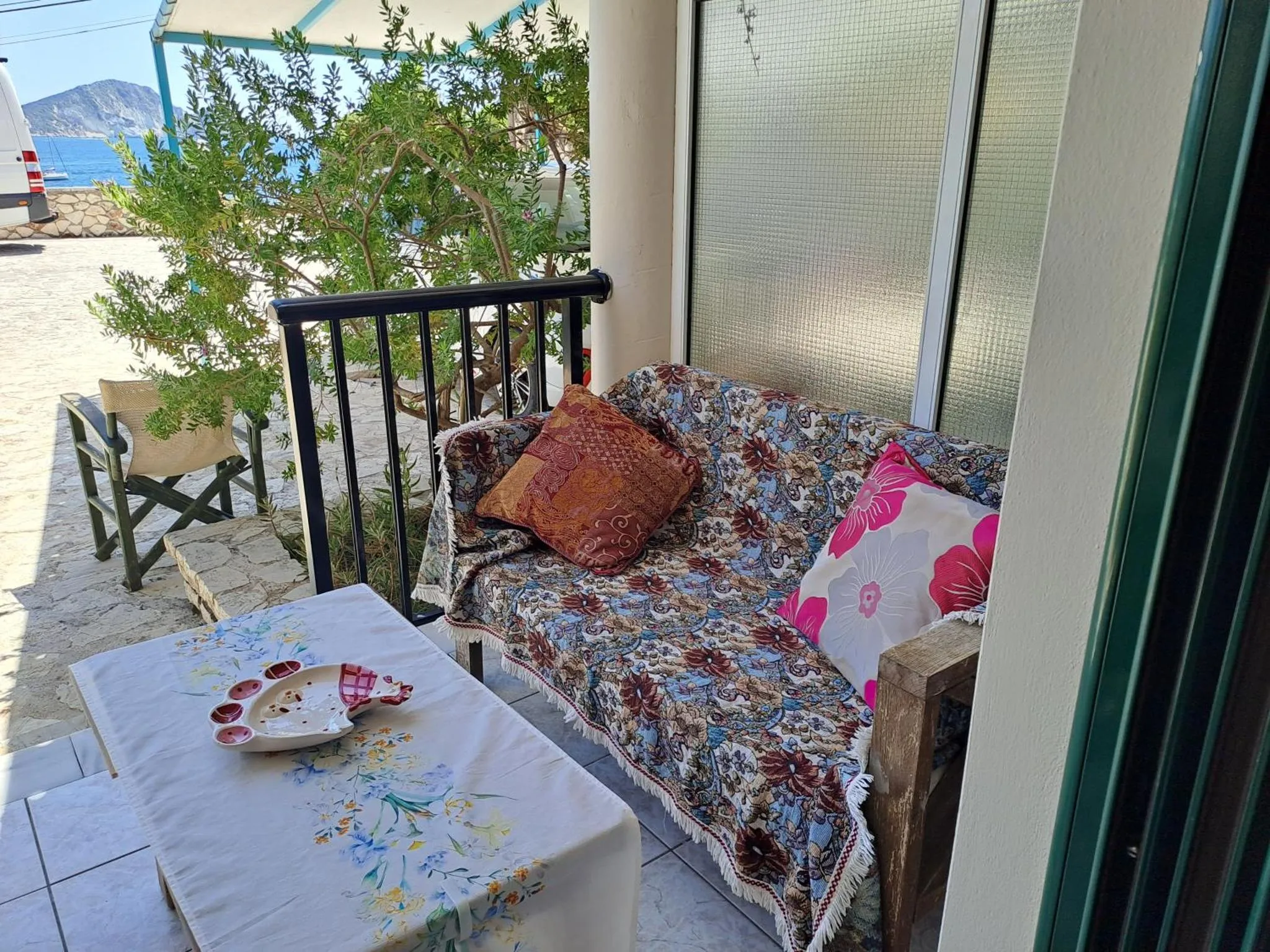 Un canapé fleuri et une table basse se trouvent sur une terrasse ombragée.