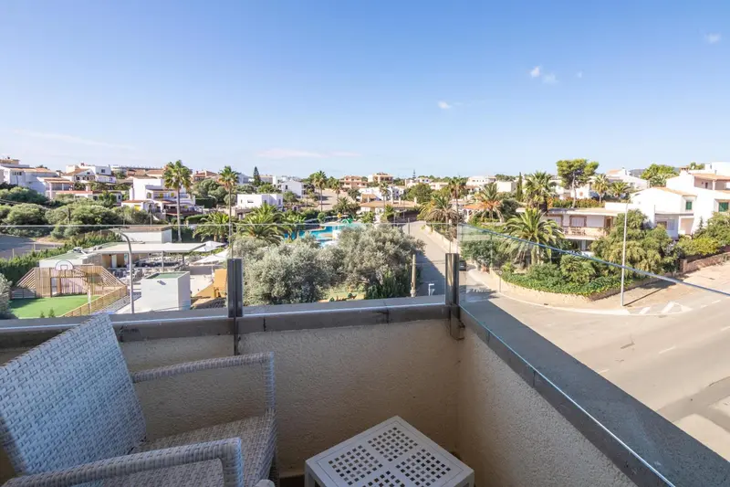 Vue d'une terrasse avec mobilier d'extérieur sur un paysage urbain et végétal.