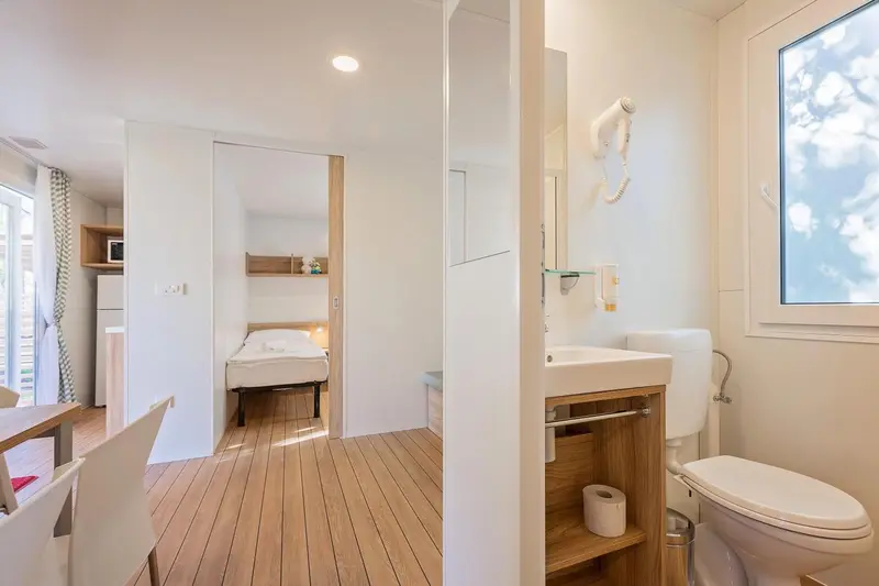 Une pièce lumineuse avec un coin repas, une chambre et une salle de bain.