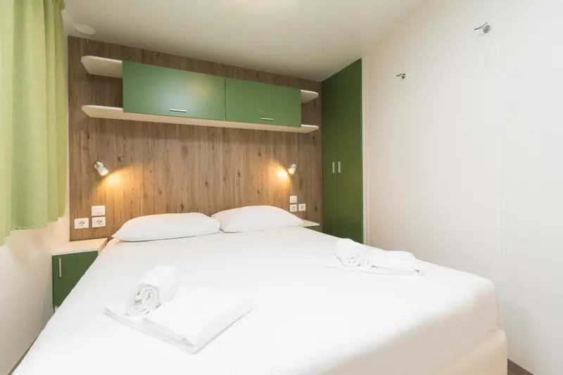 Une chambre lumineuse avec un grand lit recouvert d'une couette blanche et de serviettes.