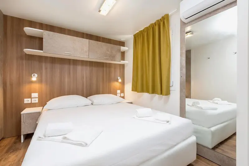 Une chambre lumineuse avec un lit double et un miroir.