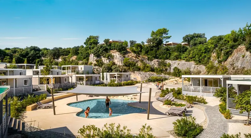 Vue aérienne d'un complexe de bungalows avec piscine et végétation luxuriante.
