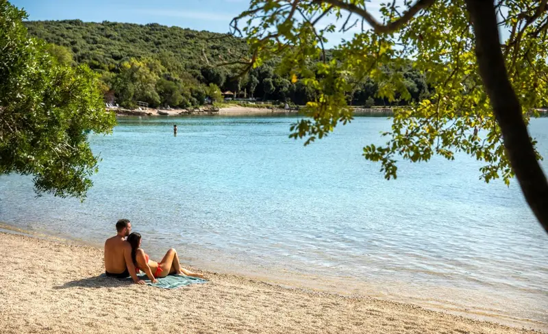 Un couple se détend sur une plage de galets au bord d'une crique abritée.