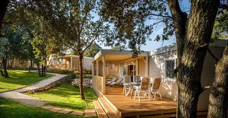 Terrasse en bois avec mobilier de jardin devant un logement clair.