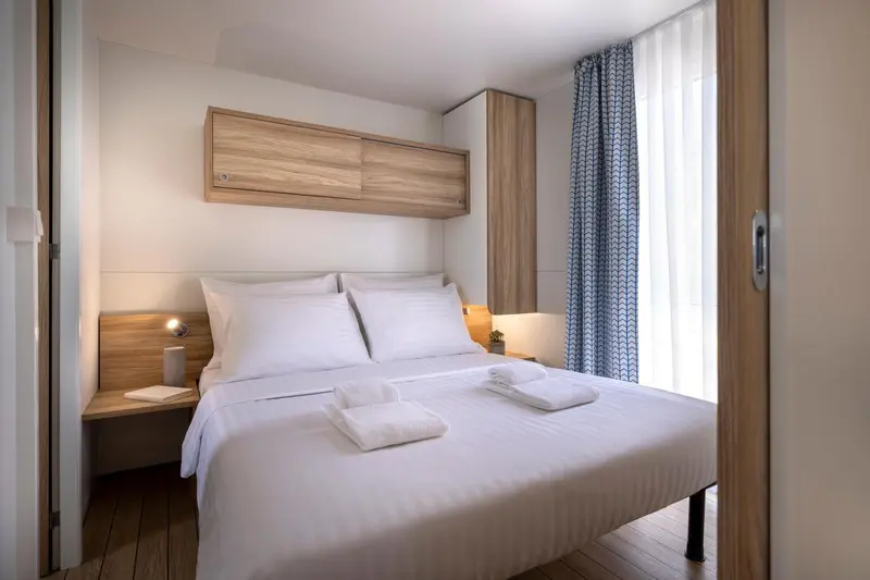 Une chambre lumineuse avec un lit double et des oreillers blancs.