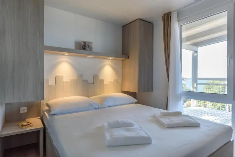 Une chambre lumineuse avec un lit double et une vue sur la végétation.